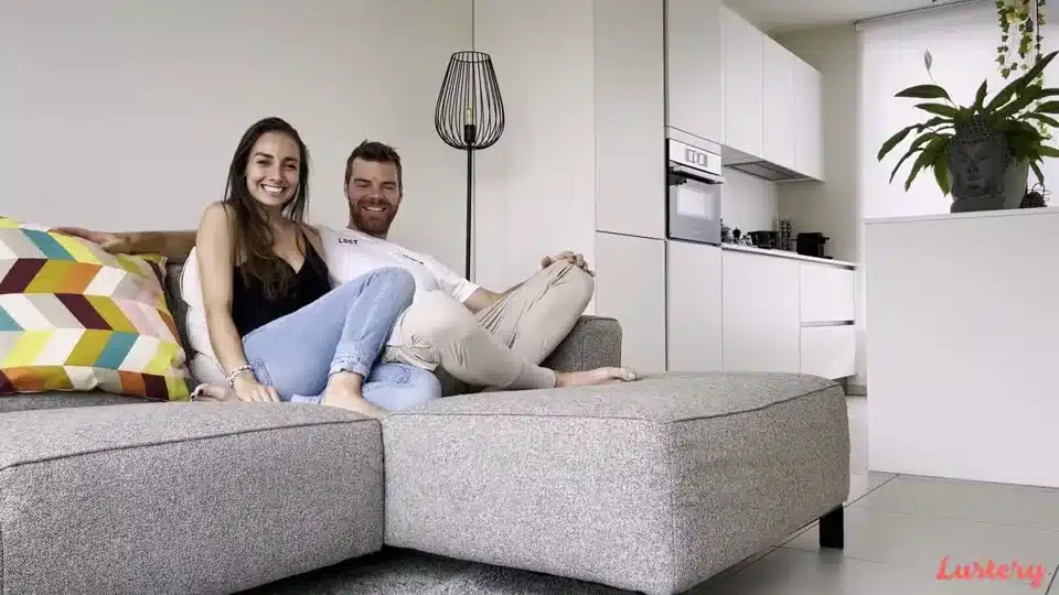 A smiling couple sitting on a sofa, image from the Lustery platform